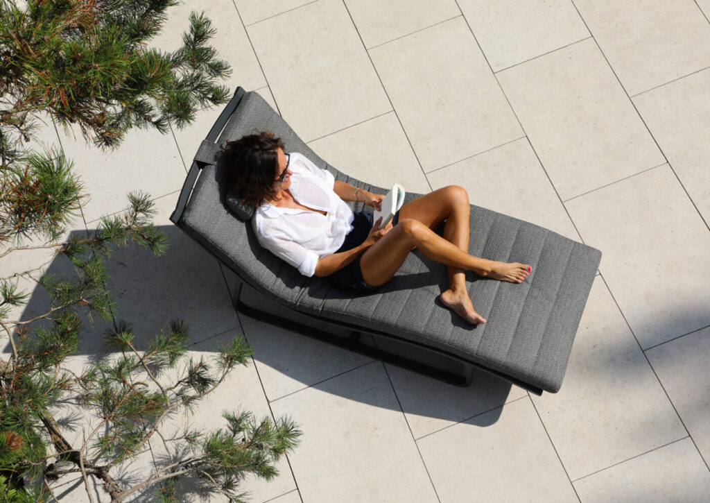 CURVED Poolliege STAY curved Lounge-Liege mit Kopfteil (L+B+H) 1615mm x 660mm x 880mm Bezug: Sunproof® steingrau Rahmen: Aluminium anthrazit Outdoor Loungemöbel aus Sunproof®-Stoff: Schönheit und Funktionalität vereint CURVED Poolliege: Outdoor Loungemöbel sind der Schlüssel zu einem luxuriösen und entspannenden Gartenbereich. Wenn diese Möbel mit Sunproof®-Stoff bezogen sind, erleben Sie eine perfekte Symbiose aus Ästhetik und Funktionalität. Sunproof®-Stoffe sind bekannt für ihre außergewöhnliche Qualität und bieten eine Vielzahl von Vorteilen, die sie zur idealen Wahl für Outdoor-Möbel machen. Vorteile von Sunproof®-Stoff für Outdoor-Loungemöbel: Langlebigkeit und Haltbarkeit: Sunproof®-Stoffe sind für ihre extreme Widerstandsfähigkeit bekannt. Sie widerstehen den harten Bedingungen im Außenbereich, einschließlich intensiver Sonneneinstrahlung, Regen und sogar Schnee. Dank ihrer speziellen Acrylfasern bleichen die Farben nicht aus und bleiben jahrelang kräftig und lebendig. Wetterbeständigkeit: Diese Stoffe sind speziell für den Outdoor-Einsatz konzipiert und bieten eine hervorragende Resistenz gegen Schimmel und Feuchtigkeit. Auch nach einem Regenschauer trocknen Sunproof®-Stoffe schnell, was die Bildung von Stockflecken verhindert und die Möbel stets frisch und einladend hält. Einfache Pflege und Reinigung: Sunproof®-Stoffe sind besonders pflegeleicht. Flecken lassen sich mühelos entfernen, oft reicht schon einfaches Abwischen mit Wasser und milder Seife. Bei hartnäckigeren Verschmutzungen kann der Stoff mit einem Hochdruckreiniger behandelt werden. Komfort und Stil: Die weiche Haptik der Sunproof®-Stoffe bietet hohen Sitzkomfort. UV-Schutz: Sunproof®-Stoffe bieten einen ausgezeichneten UV-Schutz, der nicht nur die Farben vor dem Verblassen schützt, sondern auch die Haut vor schädlichen UV-Strahlen bewahrt. Dies macht sie zur idealen Wahl für sonnige Tage im Freien. Umweltfreundlichkeit: Sunproof® legt großen Wert auf Nachhaltigkeit. Die Stoffe sind OEKO-TEX® zertifiziert und werden in umweltfreundlichen Verfahren hergestellt. Sie sind frei von schädlichen Chemikalien und tragen zu einer gesünderen Umwelt bei.