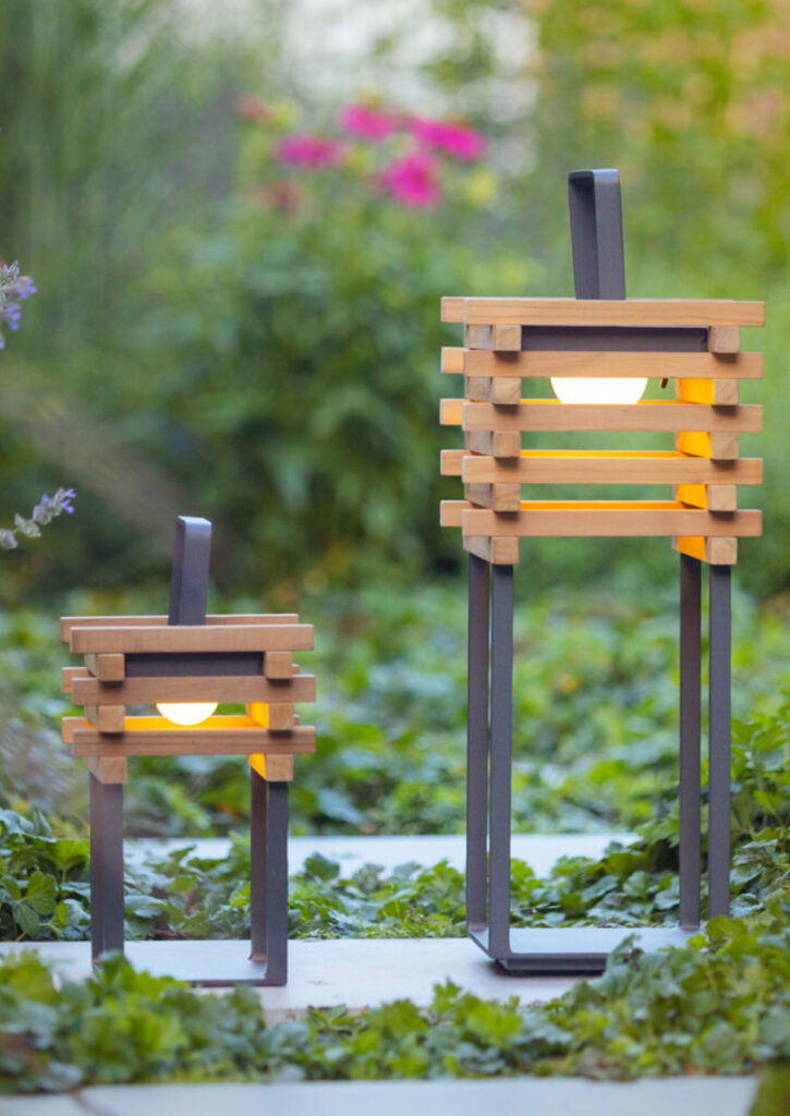 TEAK Solarlampe, 3 Stück STAY lamp tragbare Design-Außenleuchte Solarbetrieb aufladbar über USB-Anschluss dimmbar 30 – 50 – 100% Nutzung im Außenbereich (LxBxH) 230mm x 230mm x 550mm Inhalt: 3 Stück (Mindestabnahme) TEAK Solarlampe, 3 Stück: Entdecken Sie die perfekte Beleuchtungslösung für Ihren Außenbereich mit unserer tragbaren Leuchte, die aus einem robusten Aluminium-Rahmen und einem eleganten Lampenkörper aus Teakholz gefertigt ist. Diese vielseitige Solarlampe ist nicht nur ein optisches Highlight, sondern auch extrem funktional. Sie kann einfach getragen, auf den Boden gestellt oder aufgehängt werden und ist auch in einer kleineren Version als Tischleuchte erhältlich. Dank ihres modernen Designs und der hochwertigen Materialien ist diese Leuchte ideal für den dauerhaften Einsatz im Freien geeignet. Der Aluminium-Rahmen bietet hervorragende Wetterbeständigkeit und Korrosionsschutz, während das Teakholz durch seine natürliche Widerstandsfähigkeit und Langlebigkeit überzeugt. Diese Kombination sorgt für eine stilvolle und langlebige Beleuchtungslösung. Betrieben über Solarenergie oder USB, bietet diese Leuchte eine umweltfreundliche und flexible Beleuchtungsoption. Tagsüber lädt sich der integrierte Akku durch Sonnenlicht auf, und bei Bedarf kann die Lampe auch bequem über USB aufgeladen werden. Dies stellt sicher, dass Sie immer eine zuverlässige Lichtquelle zur Verfügung haben, egal ob im Garten, auf der Terrasse oder beim Camping. Die tragbare Leuchte aus Aluminium und Teakholz fügt sich harmonisch in jede Outdoor-Umgebung ein und schafft eine einladende Atmosphäre. Ob als Bodenleuchte, Hängelampe oder Tischleuchte – sie bietet vielfältige Einsatzmöglichkeiten und passt sich Ihren individuellen Bedürfnissen an. Investieren Sie in Qualität und Stil mit unserer tragbaren Solarlampe, die durch ihre Ästhetik und Funktionalität überzeugt. Verleihen Sie Ihrem Außenbereich einen Hauch von Eleganz und Nachhaltigkeit mit dieser vielseitigen Beleuchtungslösung.